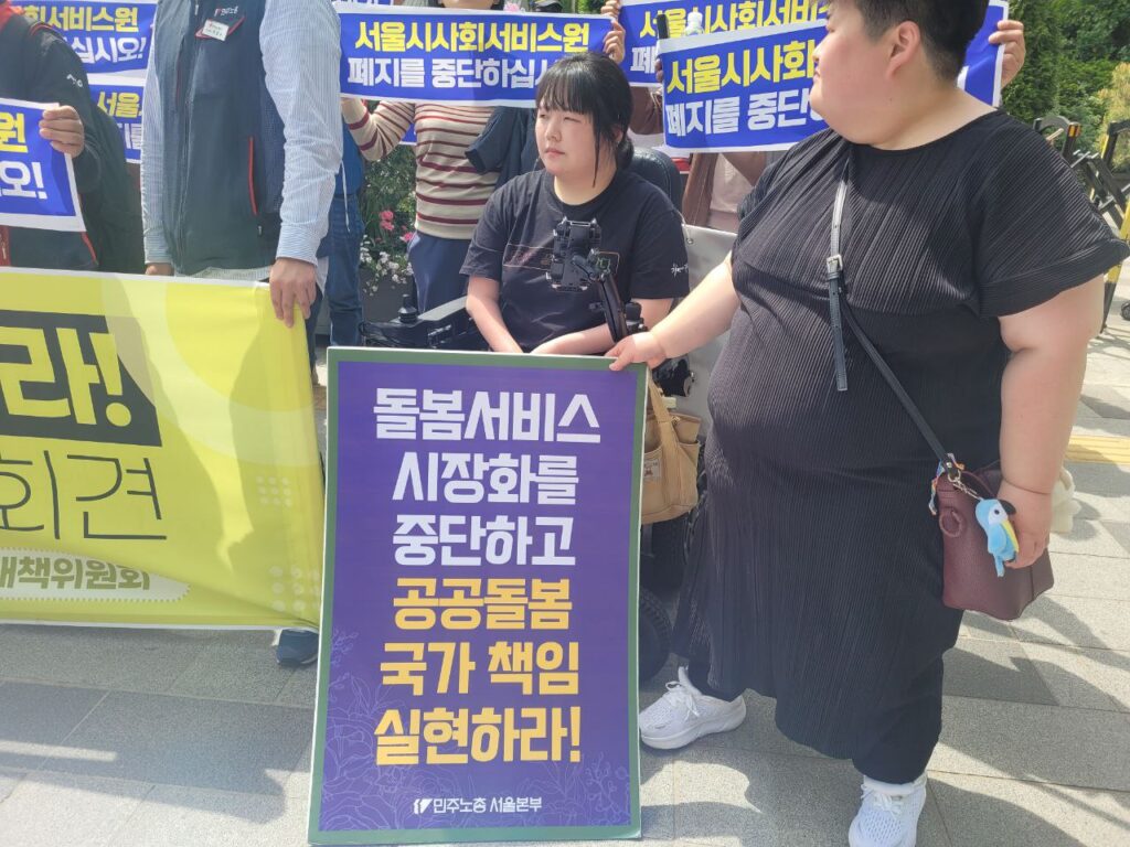 [사진 1] 24년 4월 26일 진행한 서울시사회서비스원 폐지 조례 폐기하라! 서울시의회 보건복지위원회 규탄 기자회견에 장애여성공감 활동가들이 참여한 모습. 진성선, 조화영 활동가가 ‘돌봄서비스 시장화를 중단하고 공공돌봄 국가 책임 실현하라!’라는 피켓을 들고 있다. 