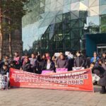 25년 2월 14일 진행된 기자회견 진행사진. 서울시청을 등지고 장애인권활동가들이 모여있다. 붉은 바탕의 현수막이 중앙에 있고 그 옆에 놓인 쓰레기봉투에는 '서울시 장애인활동지원기관 재지정심사' 문구가 부착되어있다.