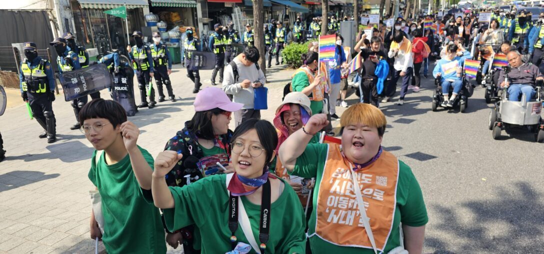장애여성권리선언대회 중 행진 모습. 대열 선두에 선 일곱빛깔무지개 회원들이 주먹을 쥐고 투쟁을 외치고 있다.  