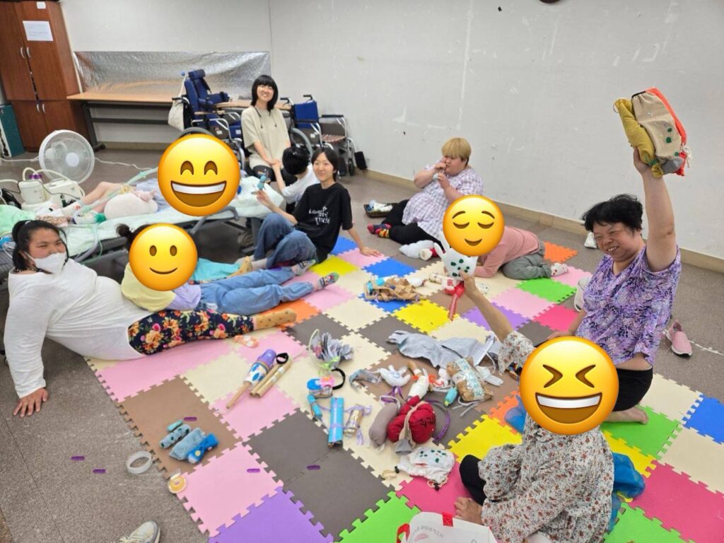 <사진 1. 2025년 16기 장애여성학교 미술반 활동사진. 참여자들이 바닥에 눕거나 앉아서 카메라를 향해 웃고 있다.>