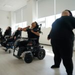 사진 1. 제주 몸이동(異動) 워크숍 첫째날. 장애여성들이 휠체어에 앉거나 바닥에 서서 상체를 뒤로 젖히거나 고개를 들며 몸을 풀고 있다.